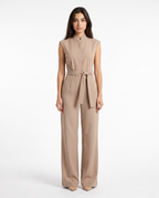 Beige jumpsuit uden ærmer med frontlukning og knyttet bælte, vide bukseben